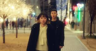 Cena noturna do dorama Itaewon Class com dois personagens caminhando em uma rua iluminada por luzes decorativas. Doramas bons na Netflix