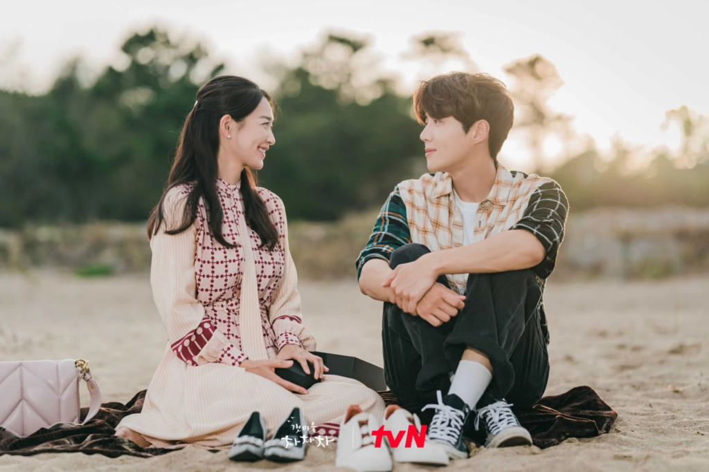 Casal sorridente em uma vila charmosa do interior, representando a atmosfera aconchegante dos doramas no interior.